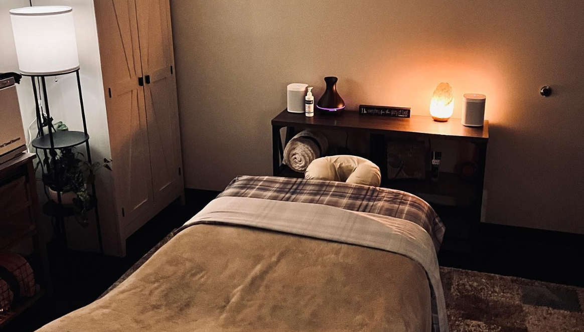 A bed with a towel and a lamp on a shelf.